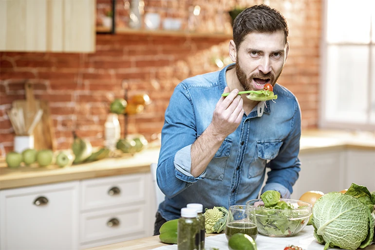 Chico con barba comiendo sano en una cocina